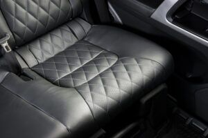 Hands installing car seat covers with hooks under a car seat.